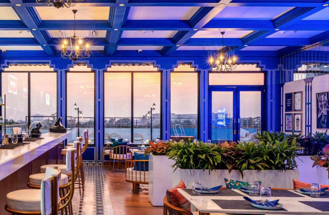 Rooftop dining room with blue framed windows and city view at Nouba Restaurant and Rooftop Lounge, C-Scheme Jaipur