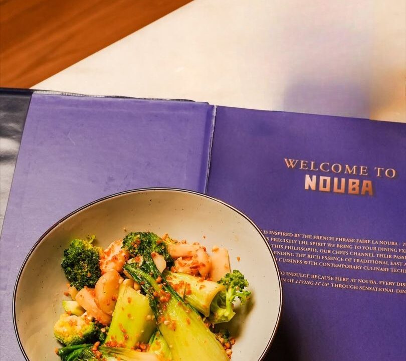 Nouba menu on a table beside a broccoli bowl at Nouba Restaurant and Rooftop Lounge, C-Scheme Jaipur