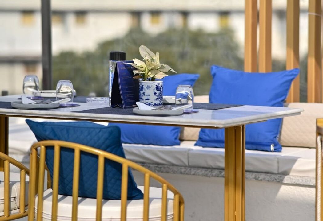 Laid table with blue cushioned seating at Nouba Restaurant and Rooftop Lounge, C-Scheme Jaipur