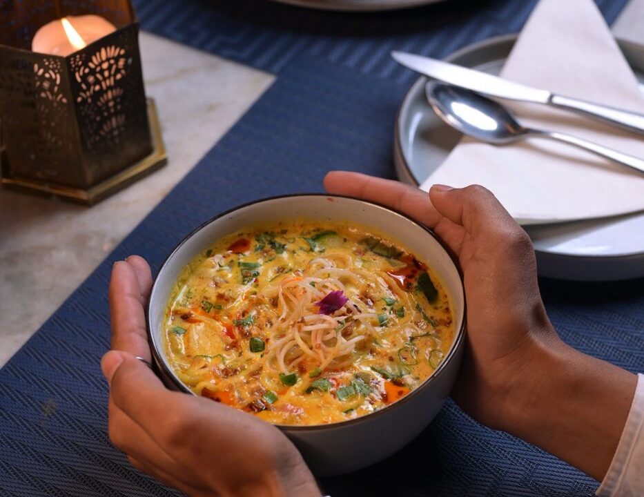 Yellow noodle bowl held in both hands at Nouba Restaurant and Rooftop Lounge, C-Scheme Jaipur