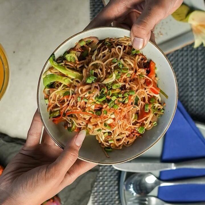 Stir fried noodle bowl held in one hand at Nouba Restaurant and Rooftop Lounge, C-Scheme Jaipur