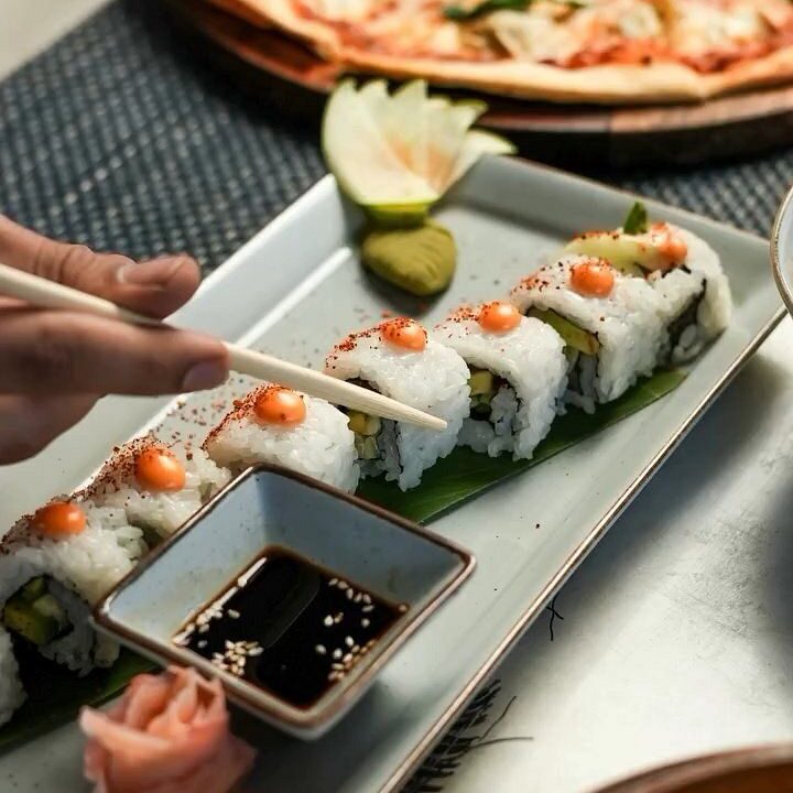 Sushi rolls being lifted from a plate at Nouba Restaurant and Rooftop Lounge, C-Scheme Jaipur