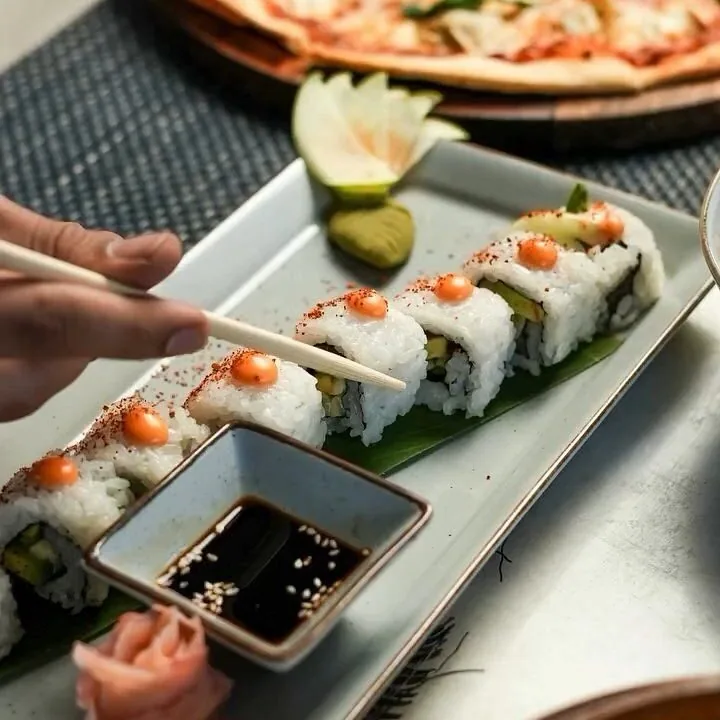 Sushi rolls being lifted from a plate at Nouba Restaurant and Rooftop Lounge, C-Scheme Jaipur