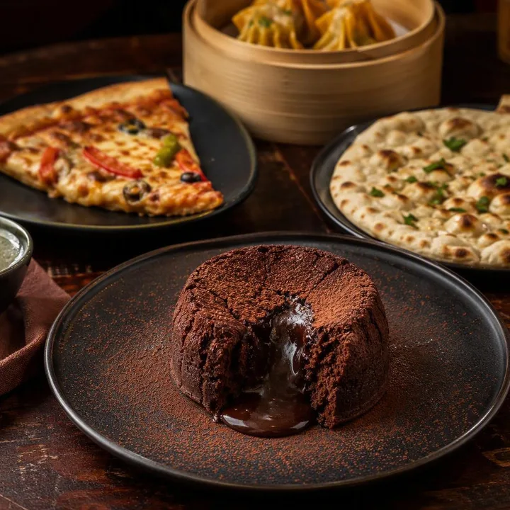 Chocolate lava cake with molten center on plate next to small dishes at Nouba Restaurant and Rooftop Lounge, C-Scheme Jaipur