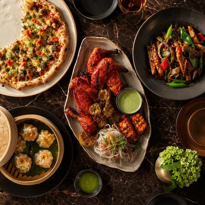 Set of shared plates from three kitchens on a long table at Nouba Restaurant and Rooftop Lounge, C-Scheme Jaipur
