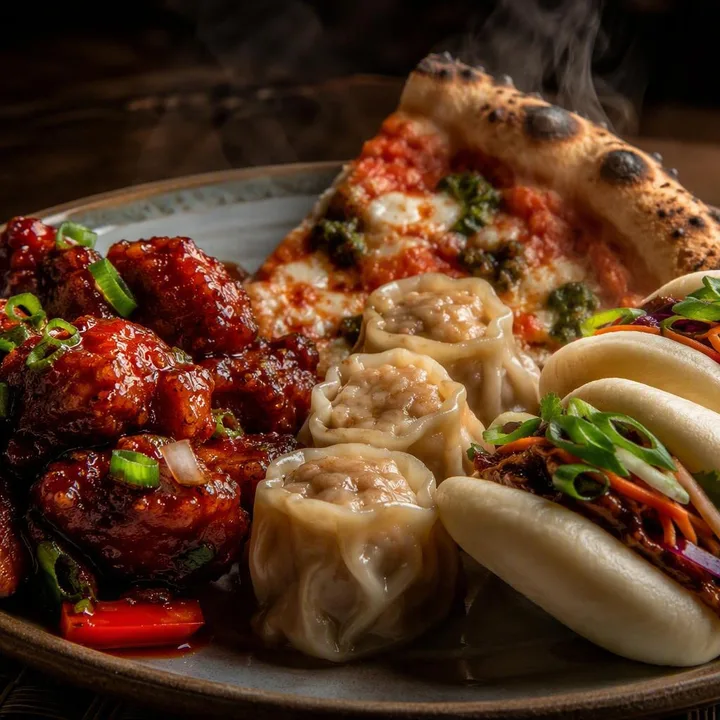 Plate of chilli chicken with dim sum and pizza on table at Nouba Restaurant and Rooftop Lounge, C-Scheme Jaipur