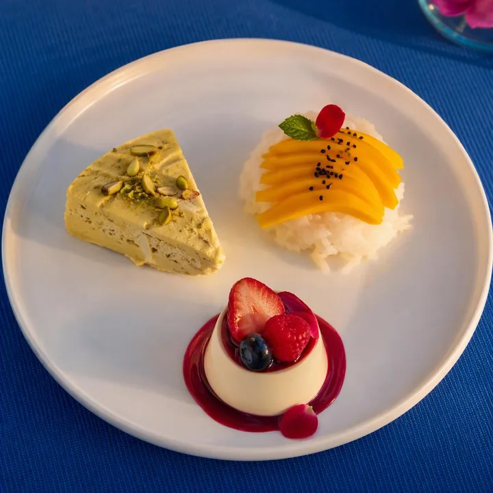 Close-up of assorted desserts on a plate with skyline backdrop at Nouba Restaurant and Rooftop Lounge, C-Scheme Jaipur
