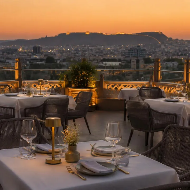 Electric blue rooftop dining area with tables and 180-degree skyline view at sunset at Nouba Restaurant and Rooftop Lounge, C-Scheme Jaipur
