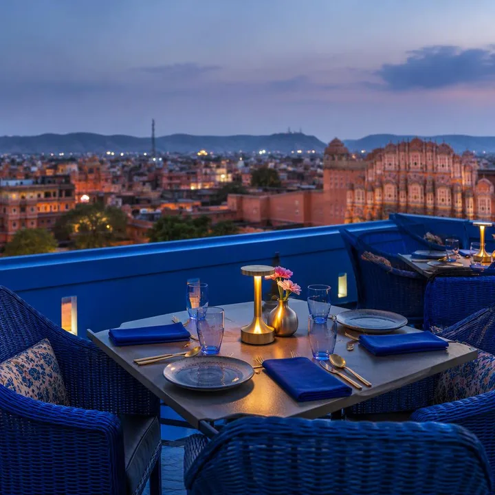 Electric blue rooftop terrace with Jaipur skyline view and tables for groups at Nouba Restaurant and Rooftop Lounge, C-Scheme Jaipur