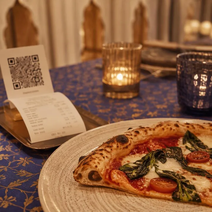 Table set for weekday lunch with wood-fired pizza and bill folder at Nouba Restaurant and Rooftop Lounge C-Scheme Jaipur