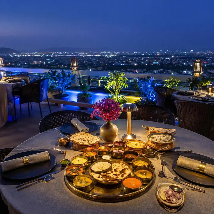 Rooftop tables with Jaipur skyline view and multiple cars on street below at Nouba Restaurant and Rooftop Lounge, C-Scheme Jaipur