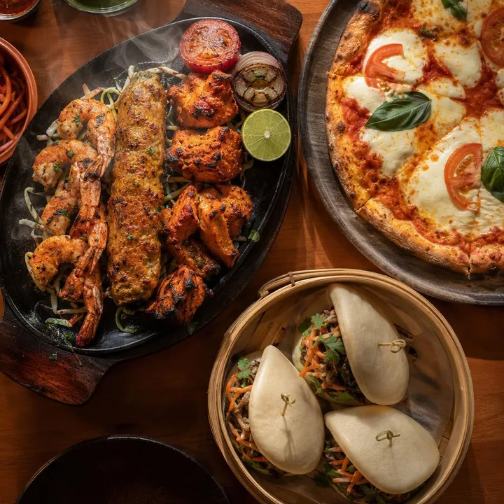 Kebab platter with pizza slice and dim sum beside it at Nouba Restaurant and Rooftop Lounge, C-Scheme Jaipur