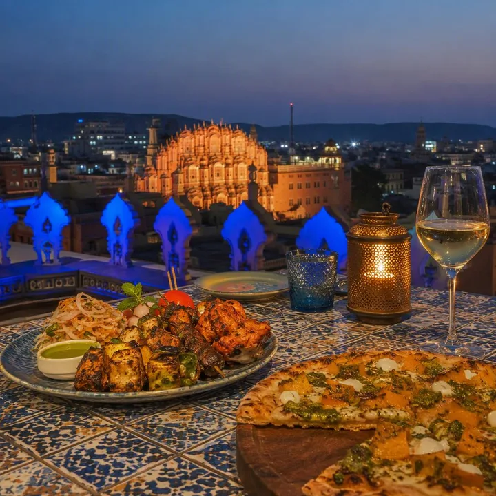 Family dinner table setup with North Indian dishes and skyline view at Nouba Restaurant and Rooftop Lounge, C-Scheme Jaipur