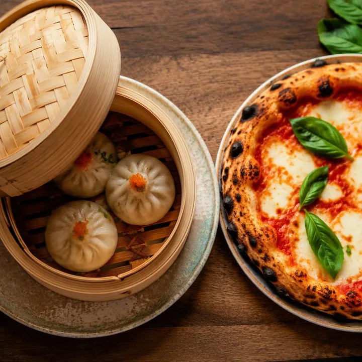 Steaming dim sum basket with chopsticks beside wood-fired pizza slice at Nouba Restaurant and Rooftop Lounge, C-Scheme Jaipur